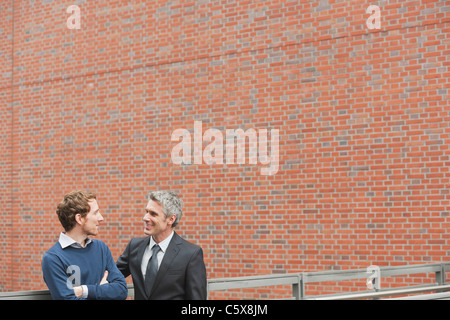 Deutschland, Hamburg, zwei Geschäftsleute sprechen vor Backsteinmauer Stockfoto
