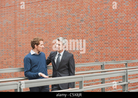 Deutschland, Hamburg, zwei Geschäftsleute sprechen vor Backsteinmauer Stockfoto