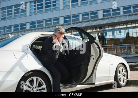 Deutschland, Hamburg, Geschäftsmann mit Handy, Auto, Seitenansicht Stockfoto