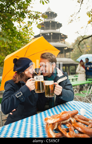 Deutschland, Bayern, englischer Garten, paar in regnerischen Bierkrüge Garten holding Stockfoto