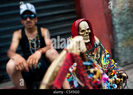 Ein mexikanischer Anhänger der Santa Muerte (Tod der Heiligen) sitzt auf der Straße während der Wallfahrt in Tepito, Mexico City, Mexiko. Stockfoto