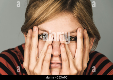 Junge Frau, die Hände auf Gesicht, Porträt, Nahaufnahme Stockfoto