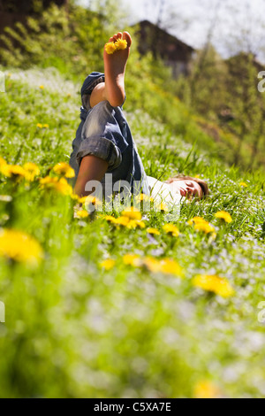 Junger Mann zum Entspannen in Wiese, Löwenzahn Blumen zwischen den Zehen Stockfoto