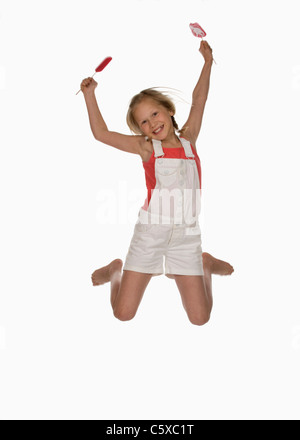 Mädchen (10-11) halten Lutscher, springen in die Luft, Lächeln, Porträt Stockfoto