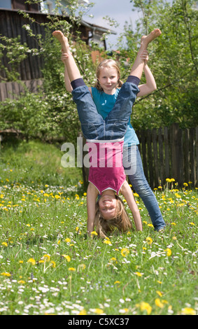 Österreich, Salzkammergut, zwei Mädchen (10-11) im Garten, helfende Freundin Handstand zu tun Stockfoto