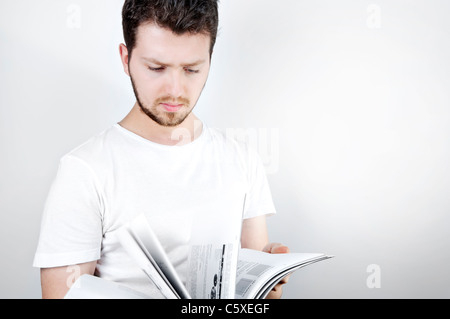 Isolierte Bild von einem jungen blonden Mann stehen und ein Fachbuch lesen Stockfoto