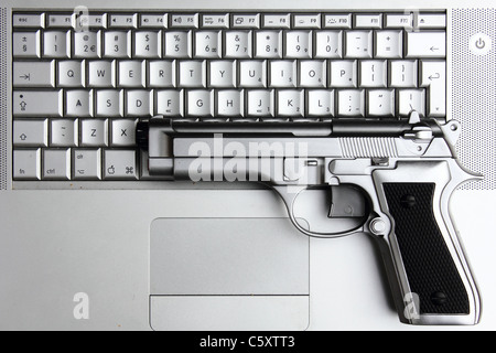 eine silberne Pistole auf einem Macbook pro Laptop, Konzeptbild, Metapher Stockfoto