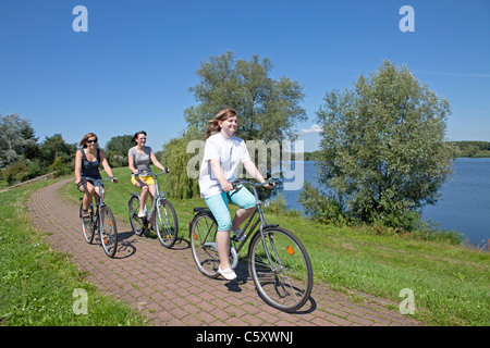 drei Mädchen, Radfahren auf dem Deich neben See Gartow, Nature Reserve Elbufer-Drawehn, Niedersachsen Stockfoto