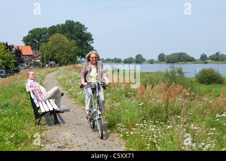 Frau, Radfahren auf dem Deich neben Fluss Elbe in der Nähe von Wussegel in der Nähe von Hitzacker, Nature Reserve Elbufer-Drawehn, Niedersachsen Stockfoto