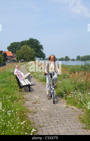 Frau, Radfahren auf dem Deich neben Fluss Elbe in der Nähe von Wussegel in der Nähe von Hitzacker, Nature Reserve Elbufer-Drawehn, Niedersachsen Stockfoto