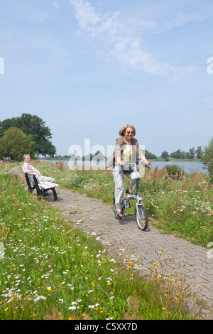 Frau, Radfahren auf dem Deich neben Fluss Elbe in der Nähe von Wussegel in der Nähe von Hitzacker, Nature Reserve Elbufer-Drawehn, Niedersachsen Stockfoto