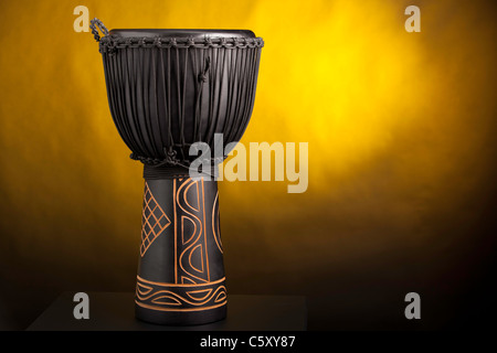 Eine schwarze Djembe Conga-Trommel gelbe Scheinwerfer im Hintergrund isoliert. Stockfoto