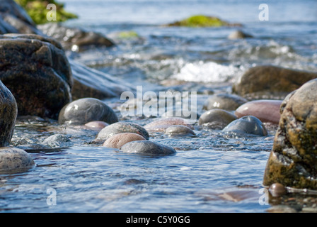 Wellen laufen über Steinen, wie die Flut auf der Insel Tiree, Schottland kommt Stockfoto