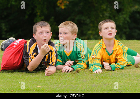 Drei Jungs im GAA Gaelic Football Outfit, liegend auf dem Rasen Stockfoto