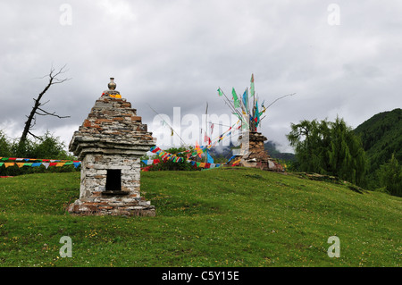 Stein-Stupa und tibetische Gebetsfahnen. Siguniang Shan Nature Reserve, Sichuan, China. Stockfoto