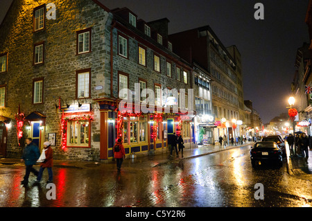 QUEBEC CITY, Kanada – Eine malerische Kopfsteinpflasterstraße in der Altstadt von Quebec glitzert nach leichtem Regen unter dem warmen Licht der Straßenlaternen. Der nasse Glanz auf der historischen Straße spiegelt die charmante Architektur und die sanfte Beleuchtung wider und schafft eine romantische Atmosphäre in diesem UNESCO-Weltkulturerbe. Stockfoto