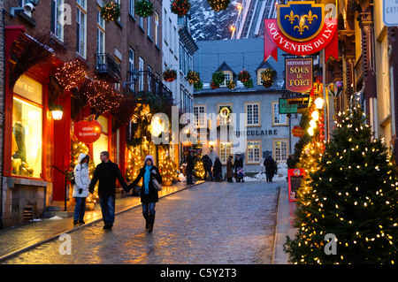 QUÉBEC CITY, Kanada – die malerische Einkaufsstraße der Rue St-Pierre in der Altstadt von Québec City, wunderschön eingerichtet für Weihnachten in der Nacht. Im Hintergrund steigt die Seilbahn die Klippe hinauf, was die festliche Atmosphäre dieses historischen Viertels während der Weihnachtszeit noch verstärkt. Stockfoto