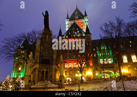 Fairmont Le Chateau Frontenac Champlain Monument beleuchtet Winternacht Quebec City Kanada / QUÉBEC CITY, Kanada — Ein Denkmal für Samuel de Champlain steht auf der Dufferin Terrasse vor dem beleuchteten Fairmont Le Château Frontenac. Die Statue wurde vom französischen Künstler Paul-Romain Chevré gestaltet und am 21. September 1898 enthüllt. Das Hotel dahinter wurde von dem amerikanischen Architekten Bruce Price für die Canadian Pacific Railway entworfen und 1893 eröffnet. Seine Chateauesque Silhouette – steile Kupferdächer, verzierte Türme und ein hoch aufragender zentraler Turm, der 1924 von William Sutherland Maxwel erweitert wurde Stockfoto