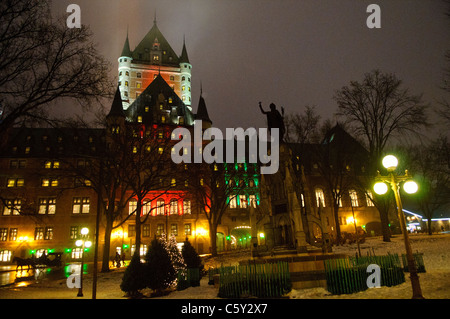 QUÉBEC STADT, Kanada – das majestätische Fairmont Le Château Frontenac, beleuchtet gegen den Nachthimmel, thront über der Altstadt von Québec. Die märchenhaften Türme und steilen Kupferdächer, die mit Schnee bedeckt sind, schaffen eine magische Winterszene in diesem historischen UNESCO-Weltkulturerbe. Stockfoto