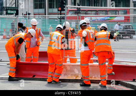 Teamwork arbeitet zusammen viele Hände machen leichte Arbeit sieben Arbeiter, hochsichtbare Kleidung, stellen Stahlzaun in Victoria London, England, Großbritannien, auf Stockfoto