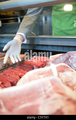 Eine Hand zeigt die verschiedenen Fleisch-Optionen an einer Frischfleisch-Theke Stockfoto