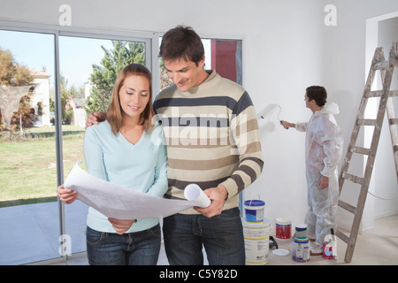 Paar durchläuft Haus planen und Maler im Hintergrund Stockfoto