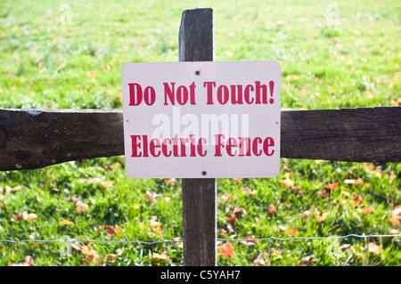 Ein Warnzeichen für einen elektrischen Zaun, auf einem Bauernhof in Hudson Valley, New York, USA. Das Schild liest "Nicht berühren! Elektrischen Zaun". Stockfoto