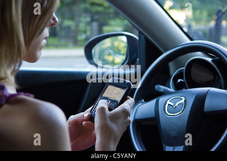 Frau im Auto mit Telefon GPS, um Wegbeschreibungen zu finden Stockfoto