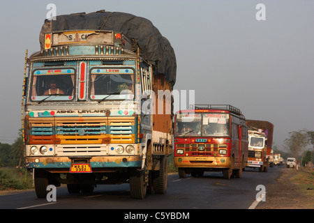 Konvoi von LKW und Bussen bei Sonnenuntergang auf der nationalen Landstraße, Westbengalen, Indien Stockfoto