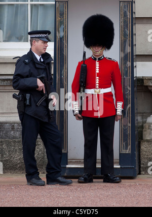 Grenadier-Garde und Polizist außerhalb Buckingham Palace in London, England Stockfoto