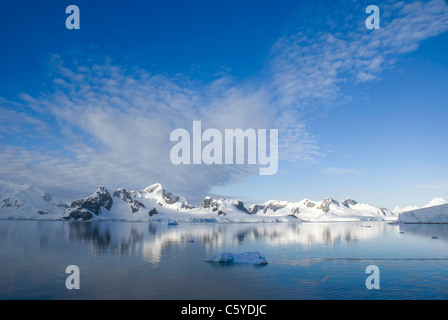 Tiefblauer Himmel mit Schnee bedeckten Bergen und Eisberg im Vordergrund mit ruhigem Wasser. Aufgenommen am Paradies Hafen, Antarktis. Stockfoto