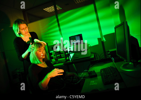 Neurowissenschaftler mit Schlüssel förmigen Paddel Transcranial magnetische Anregung TMS Thema sitzen im Labor Lit grüne durchführen Stockfoto