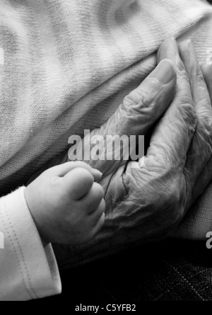Ein weiches Baby geballten Hand neben eine alte faltige Alter Hand in schwarz / weiß Stockfoto