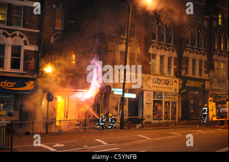 Feuerwehrleute bekämpfen ein Feuer im Party Superstore, das von Randalierern während einer Nacht der Unruhen in Clapham Junction, South London, angezündet wird. Stockfoto