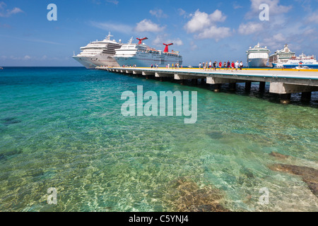 Kreuzfahrtschiffen Sie Passagiere von auf Pier Aussteigen aus Karneval Kreuzfahrt-Schiffe, Triumph und Ekstase in Cozumel, Mexiko Stockfoto