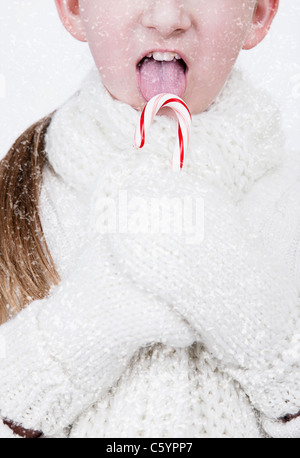 USA, Illinois, Metamora, Mädchen (6-7) Wolle Handschuhe und Schal leckt Zuckerstange Stockfoto