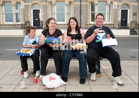 eine Familie - Mutter, Vater, Tochter, Sohn, Essen Fisch und Chips, sitzen auf einer Bank, Großbritannien Stockfoto