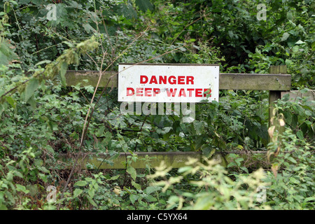 Die Gefahr einer tiefen Wasser Warnschild im Sommer Unterholz auf einem Pfad in grovely Woods, Wilton, wiltshire Grossbritannien. Stockfoto