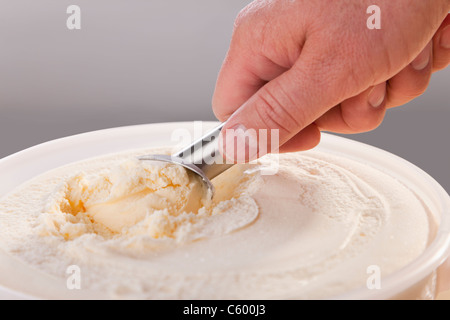 Mans Hand schöpfen Vanilleeis aus Wanne Stockfoto