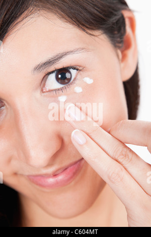 Junge Frau, die Anwendung der Feuchtigkeitscreme unter Auge Stockfoto