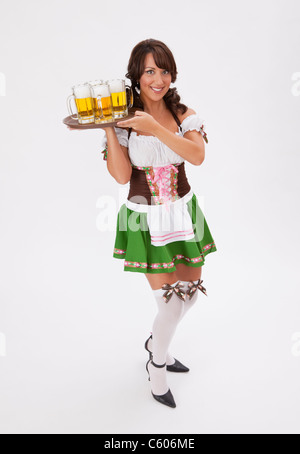 Junge Frau trägt Oktoberfest Kostüm hält Tablett mit Bier, Studio gedreht Stockfoto