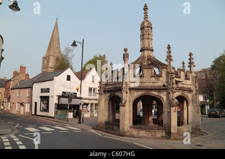 Markt Kreuz mit Malmesbury Abbey hinter in Malmesbury, Cotswolds, Wiltshire, England. Stockfoto