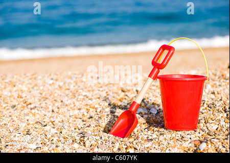 Roter Kinder Spielzeug Eimer und Schaufel am Strand Stockfoto