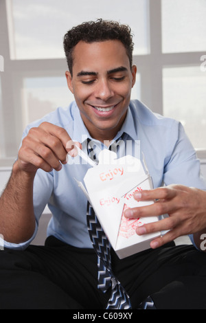 USA, New York, New York City, lächelnde junge Mann isst Chinise Essen Stockfoto