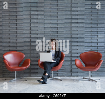 USA, New York, New York City, lächelnde junge Frau mit Laptop in der Lobby des Hotels Stockfoto