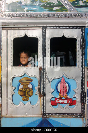 Kleines Kind Gleichaltrigen aus lokal gestaltete verzierten Fenster eines Nepali tata Lkw butwal Nepal Stockfoto