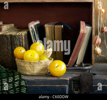 Stillleben mit Büchern und gelben Pflaumen Stockfoto