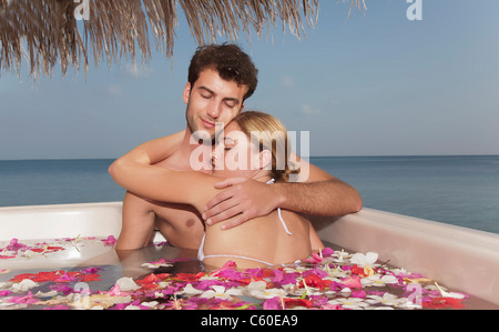 Paar, umarmen im Pool mit Blütenblättern Stockfoto
