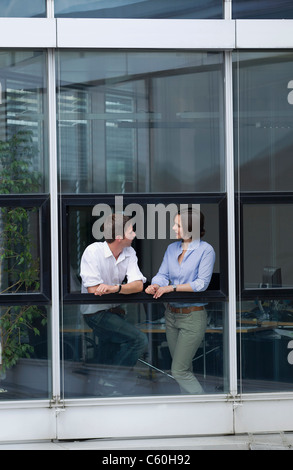 Geschäftsleute, die am Bürofenster im Gespräch Stockfoto