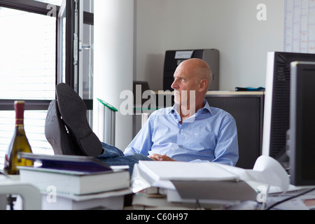 Geschäftsmann entspannend mit Füßen auf Schreibtisch Stockfoto